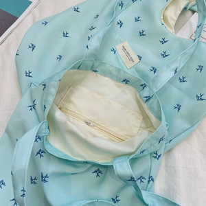 Detail view of the mint green canvas tote interior with zipper pocket and bird print