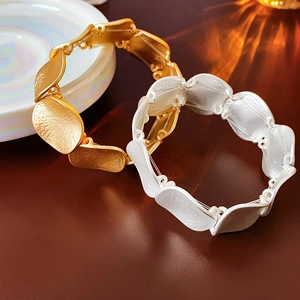 Close-up of minimalist circular metal bracelets with matte gold and silver leaf textures