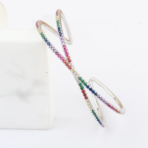 Macro detail of rainbow zircon open bangle with colorful stones on white marble base