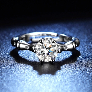 Macro shot of silver six-prong moissanite ring with unique bamboo style band on blue background