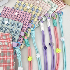 Detail of plaid crossbody phone bags with snap buttons and adjustable colorful lanyards