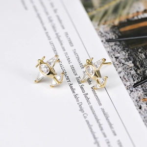 Detailed view of airplane stud earrings with inlaid cubic zirconia on a gold base