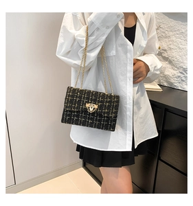 Chic black tweed chain shoulder bag shown with white shirt for a stylish summer look