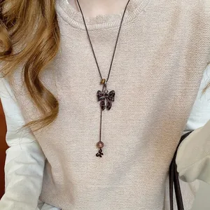 Sautoir en Y vintage avec nœud imprimé léopard et perles brunes sur un pull beige