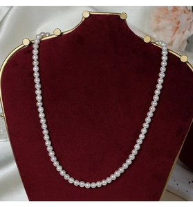 Close-up of 5-6mm natural freshwater pearls displayed on a red velvet jewelry stand