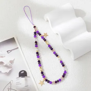 Detail shot of purple crystal beaded phone strap with gold star charms on a white background
