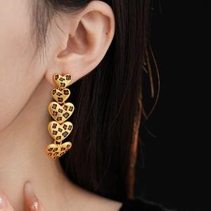Close-up of dangling gold heart earrings with vintage leopard print on female model