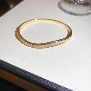 Detailed close-up of 18k gold-plated bangle with double-row wave-shaped zirconia stones