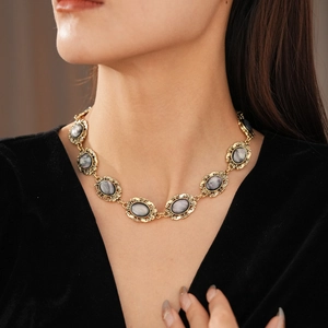 Detail of vintage gray resin oval link necklace with gold frames on black velvet top