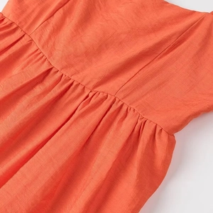 Vue détaillée du tissu en lin orange avec des plis à la taille et des coutures de haute qualité