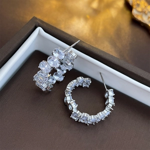Close-up of silver C-shaped hoop earrings with oval crystals in a jewelry box
