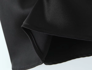 Detailaufnahme von schwarzem Satinstoff mit Präzisionsnähten und hochwertigem Saum