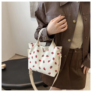 Detail of cream corduroy handbag with strawberry embroidery carried by model