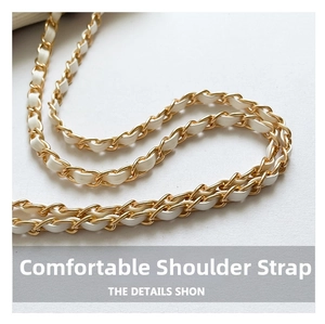 Detailed macro view of the woven gold metal chain and white leather shoulder strap