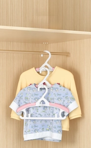 Close-up of stackable baby hangers showing the space-saving vertical hook and pink non-slip pads