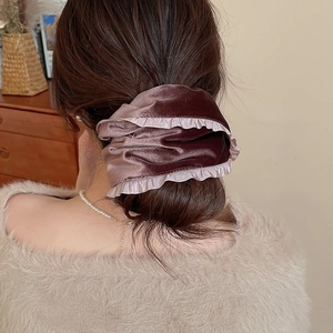 Close-up of a large brown velvet scrunchie with lace edges on a woman's ponytail
