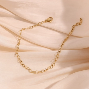 Close-up of 14K gold plated heart link bracelet on elegant beige silk fabric texture