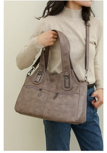 Detail of taupe faux leather tote with vintage texture and bronze zipper front pockets