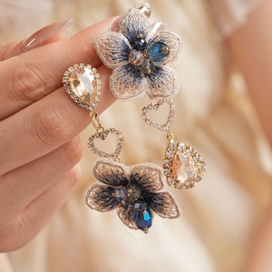 Détail macro de boucles d'oreilles vintage brodées de fleurs bleues avec goutte en cristal