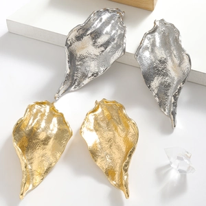 Exaggerated metal leaf-shaped earrings in gold and silver with textured hammered finish