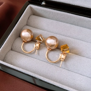 Gros plan de boucles d'oreilles perles dorées avec cristal ambré en boîte cadeau