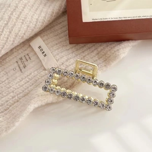 Detail of elegant gold metal hair claw clip with pavé white rhinestones in rectangular shape