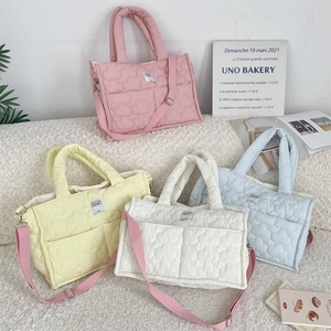 Dettaglio di borse tote trapuntate in rosa pastello, giallo, bianco e azzurro su peluche