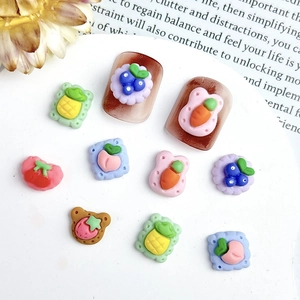 Flat lay of resin fruit and cookie nail charms featuring strawberry and pineapple designs