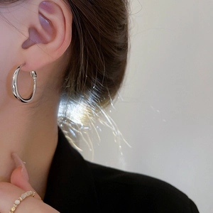 Boucles d'oreilles créoles géométriques minimalistes en métal argenté sur un mannequin
