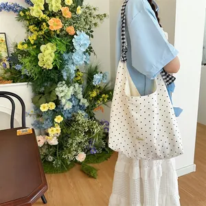 Detailed view of polka dot canvas tote bag with check patterned straps and side seam stitching