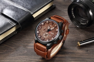 Detail of a CURREN men's quartz watch with brown leather strap on a rustic wooden desk