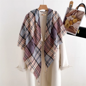 Detailed view of checkered cashmere-like scarf with tassels over a white coat