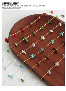 Detail of delicate gold chains with multi-color natural tiger eye stones on wooden tray
