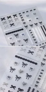 Detailed view of black and white bow nail stickers with lace patterns and heart designs
