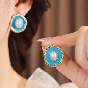 Detail of vintage oval drop earring with blue enamel and pearl on gold textured border