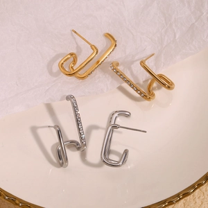 Macro shot of asymmetric double-layer 18K gold earrings with sparkling pave zircon accents