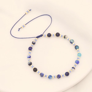 Handmade bohemian beaded bracelet with natural blue stones and gold spacers on white background