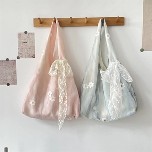 Close-up of floral embroidery detail and large lace bow on stylish canvas tote bags