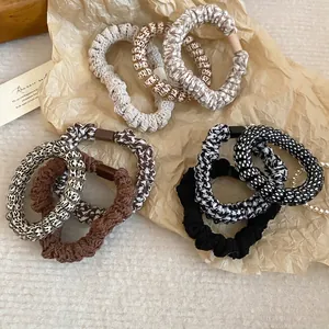 Elastic fabric hair ties set in beige and brown tones with pearl details on paper