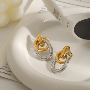 Boucles d'oreilles minimalistes bicolores en acier inoxydable sur plateau blanc