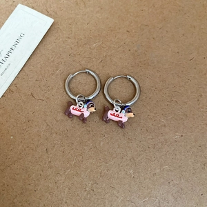 Detail of dachshund dog earrings with pink enamel finish on textured background
