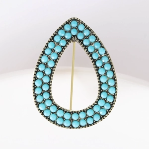 Detailed view of the pear-shaped vintage alloy brooch with turquoise bead embellishments