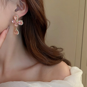 Close-up of pink crystal butterfly drop earrings with rhinestones worn by a model