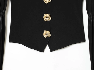 Dettaglio della maglia nera slim fit con bottoni decorativi a forma di rosa dorata e maglia