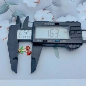 Detail showing red cherry charm measurement of 16.3mm with a digital caliper tool