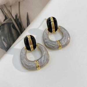 Detailed shot of vintage gold-plated enamel earrings with marble resin pendants on a card