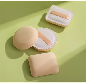 Set mit vier beigen runden und eckigen Make-up-Quasten mit orangefarbenen Bändern