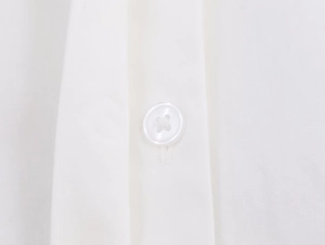 Detailed macro view of white resin buttons and fine poplin stitching on shirt front