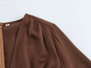 Close-up of elegant V-neckline and shoulder detail on a brown satin chiffon long dress