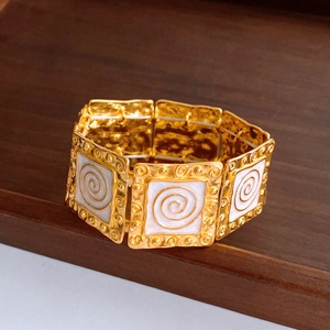 Detail of vintage gold-tone chain bracelet with white enamel and spiral geometric patterns